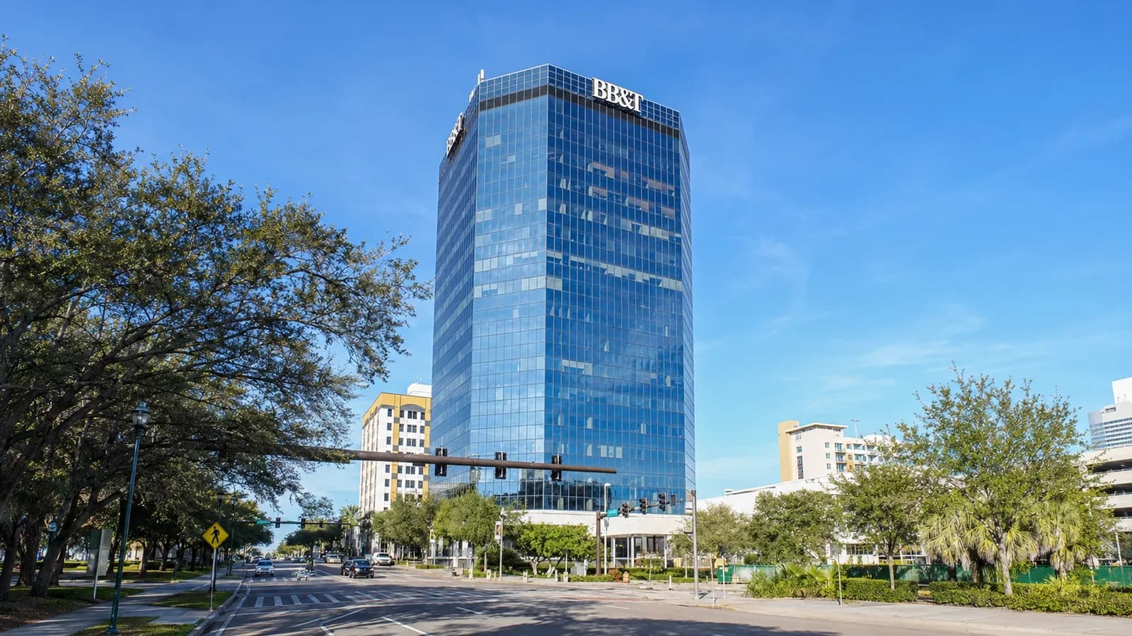 The glass tower at 360 Central Avenue in downtown St. Petersburg, Florida, seen from the palm-lined street below.