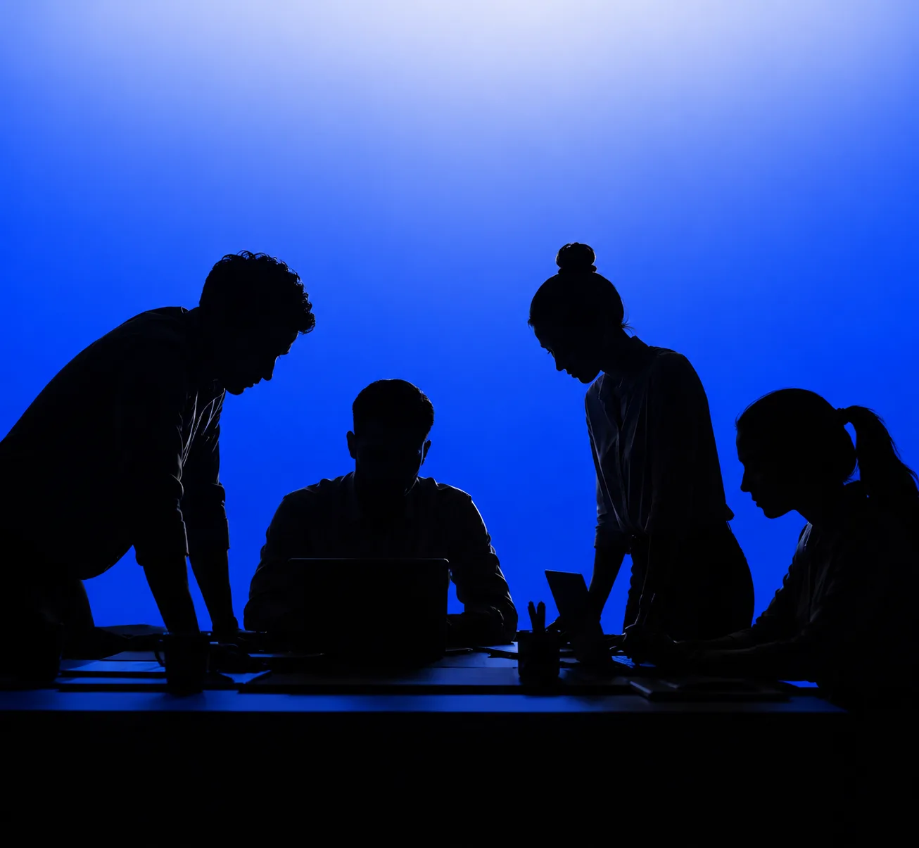 Strategists and engineers gathered around a laptop, working through a plan together.